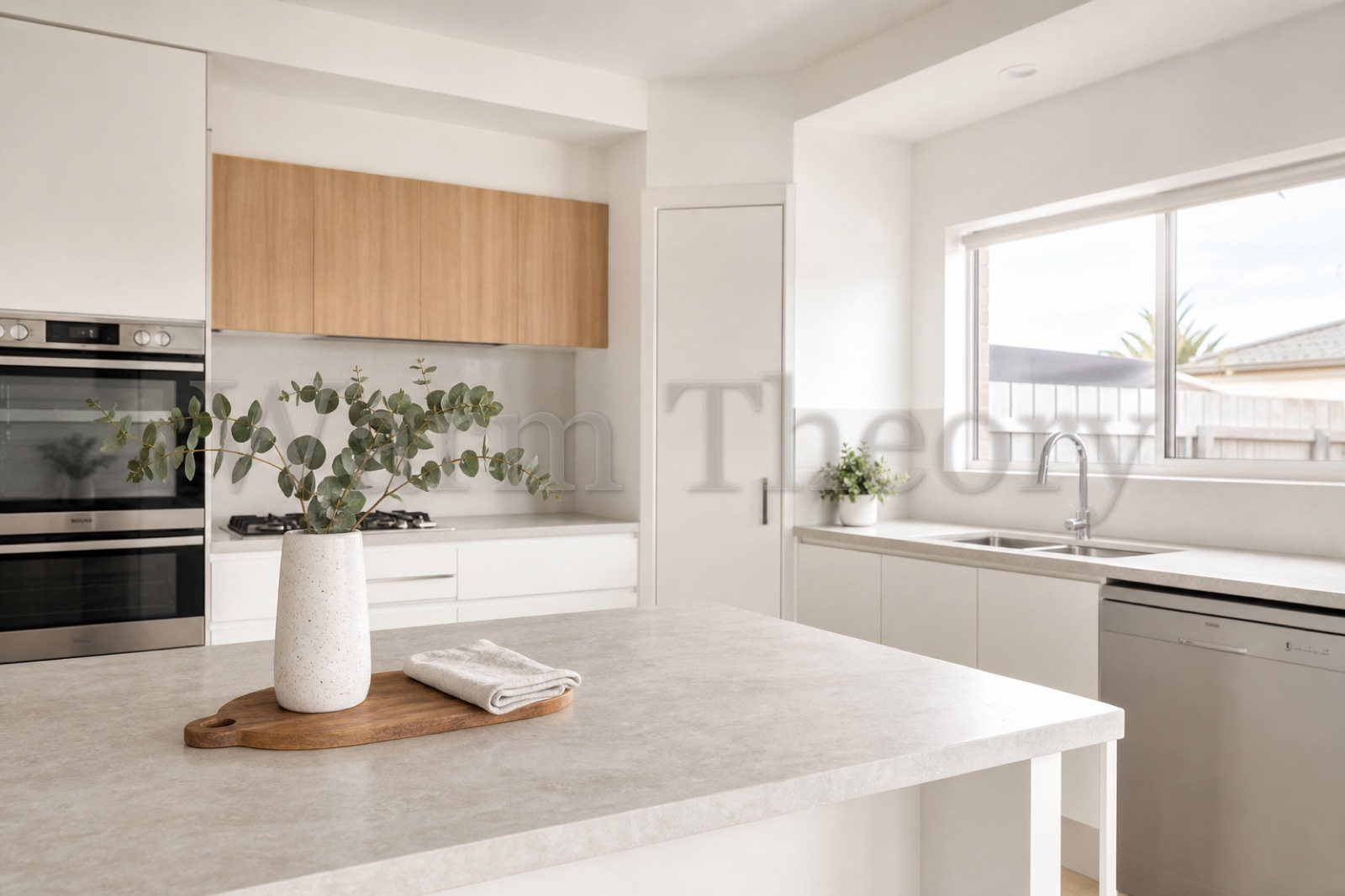 Plain white and oak kitchen with simple styling and a eucalyptus vase on the benchtop