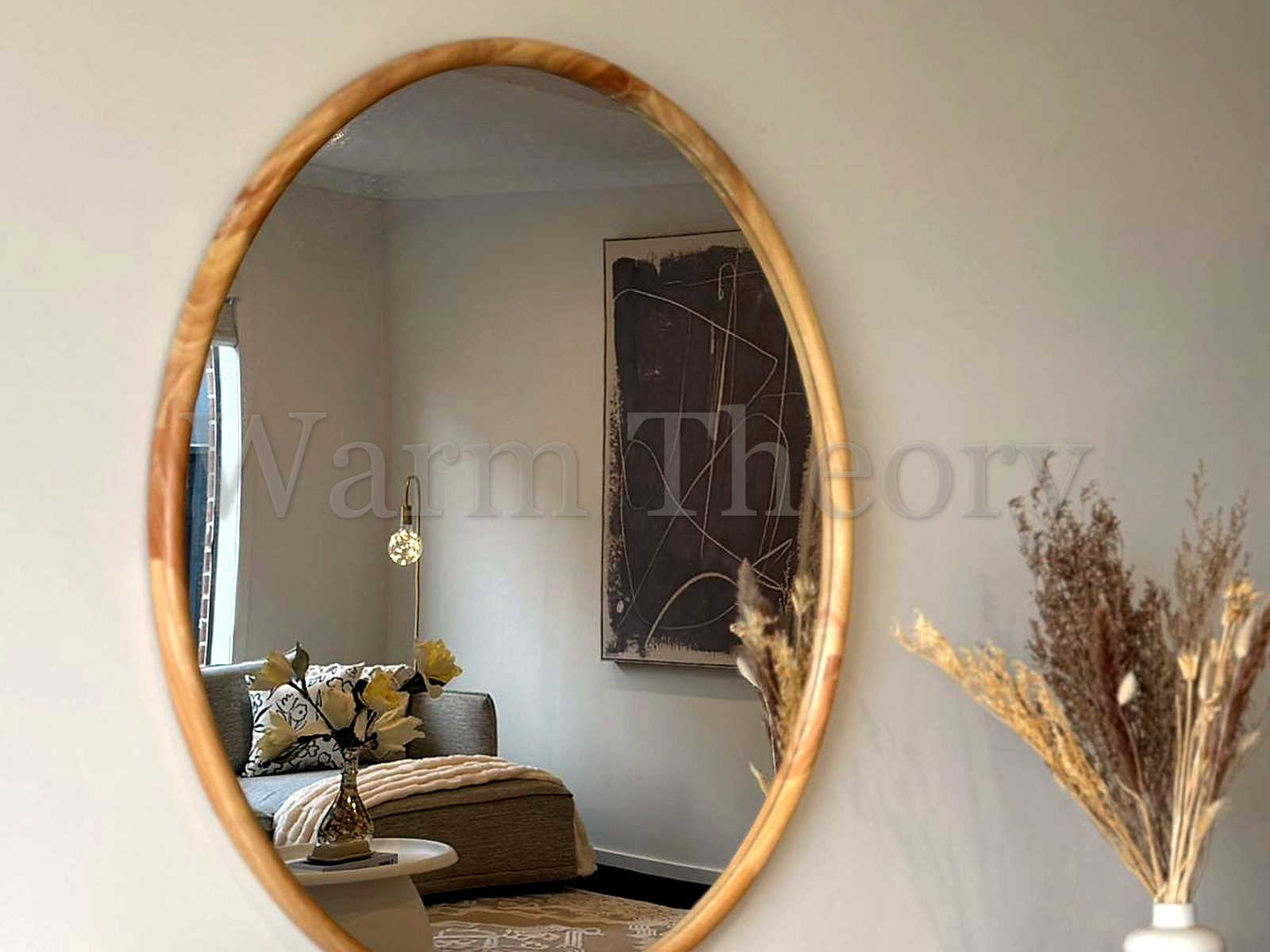 Dresser vignette with a round timber-framed mirror, a beaded tray, and dried florals on a light timber console