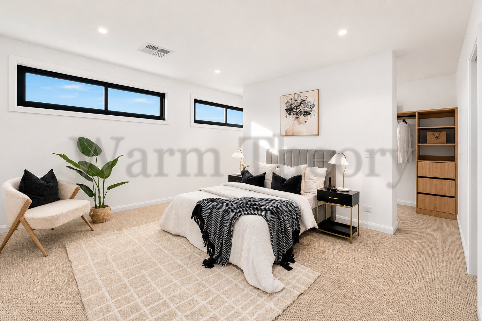 Master bedroom with a grey upholstered bed, black and gold bedside tables, a boucle accent chair, and a walk-in robe